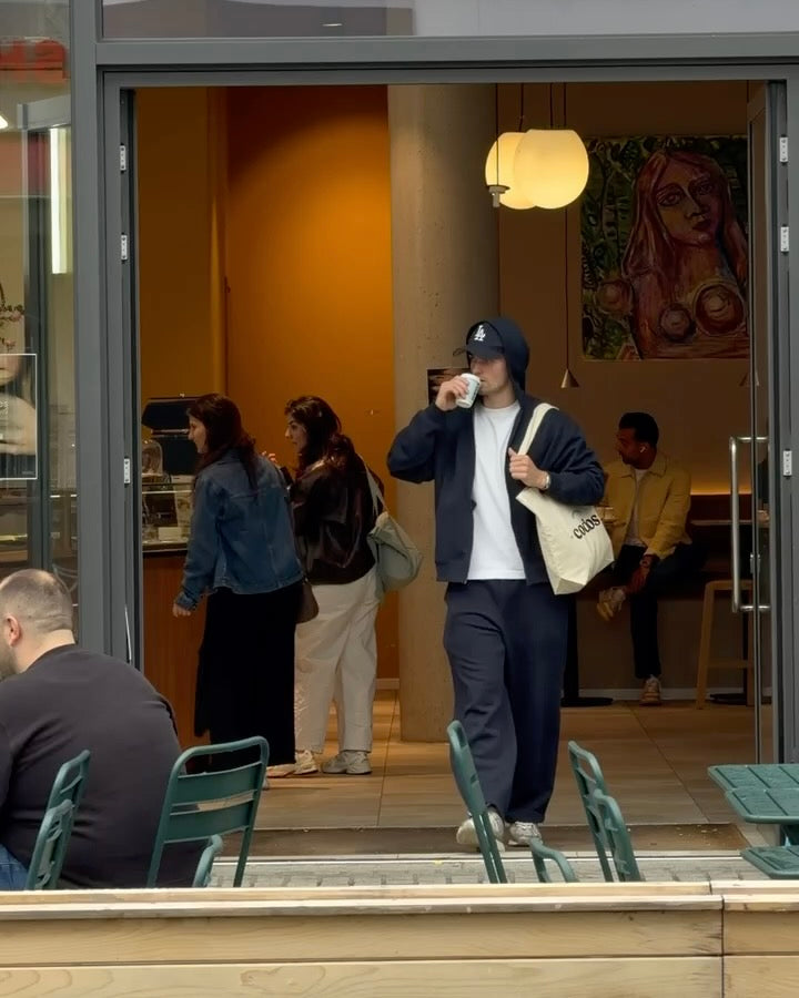 Video of man walking with a codos canvas bag, out of codos drinking from a to-go cup