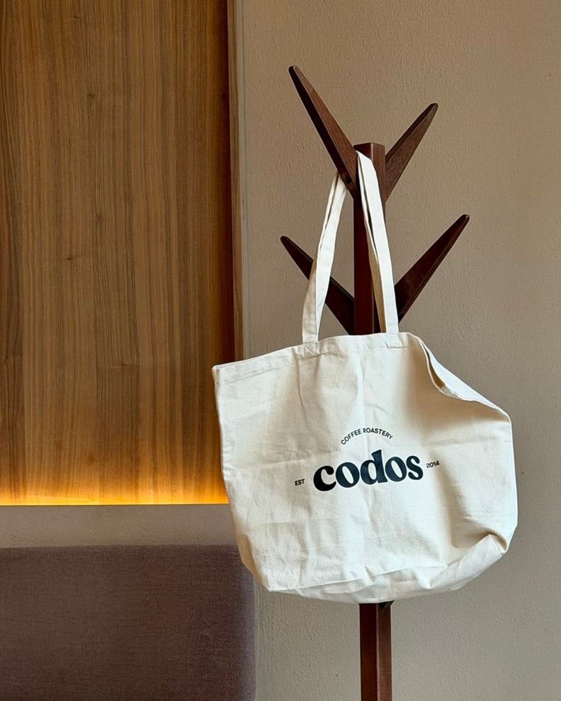 tote bag hanging from a coat holder with the codos logo