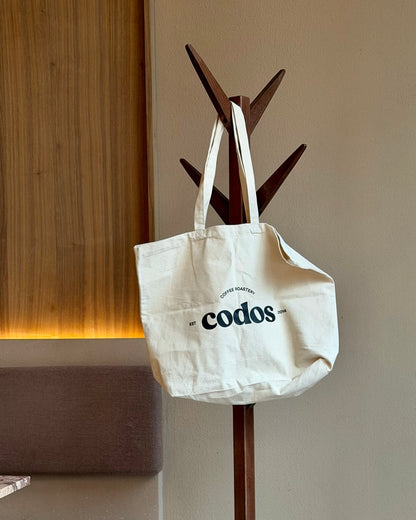 tote bag hanging from a coat holder with the codos logo